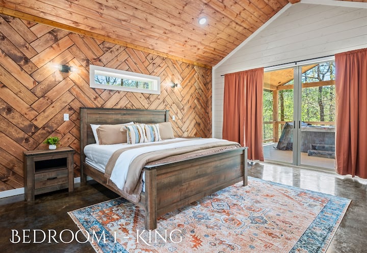 Escape to this warm and inviting master bedroom, where rich wooden tones meet a cozy bed, framed by an intricate herringbone accent wall