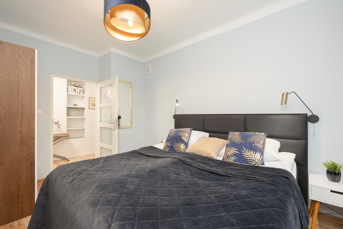 Un dormitorio acogedor con una lujosa colcha de color gris oscuro e iluminación suave, perfecto para relajarse.