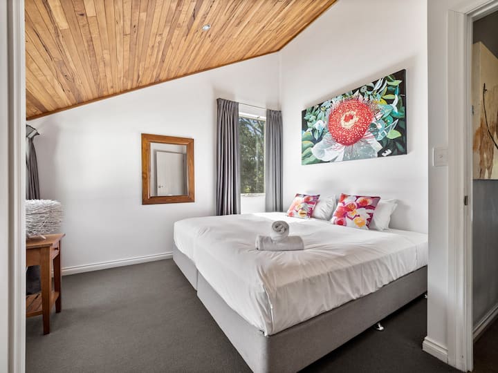 Спете под тавана, облицован с дървен материал в третата спалня - място за отдих, изпълнено с изкуство, със суперголямо двойно легло и спокойни гледки.