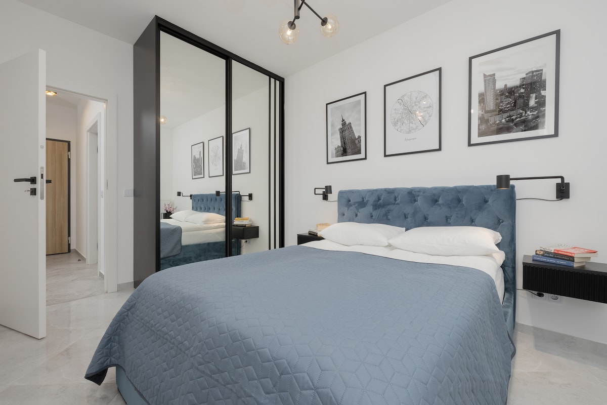 卧室内有一张蓝色床罩、墙面艺术品和简约设计。