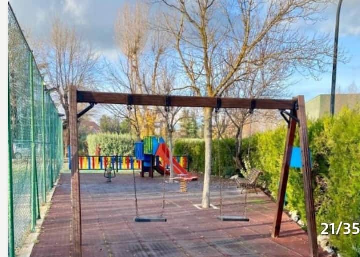 Parque infantil de la urbanización con columpios y tobogán: diversión asegurada para los más peques.