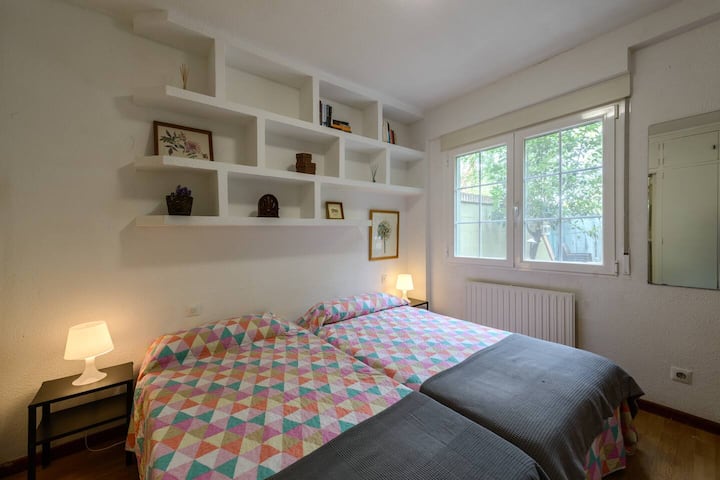 Dormitorio con estanterías de obra y gran ventanal: espacio luminoso con mucho sitio para guardar.