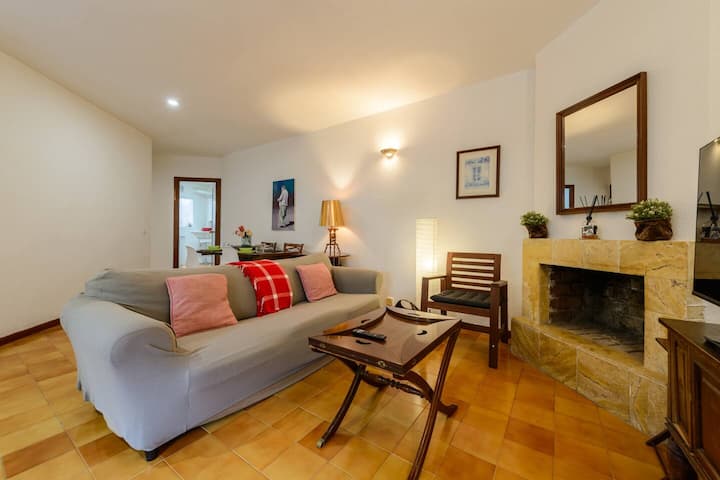 Salón con sofá gris, cojines rojos y mesita de madera: rincón acogedor para desconectar.