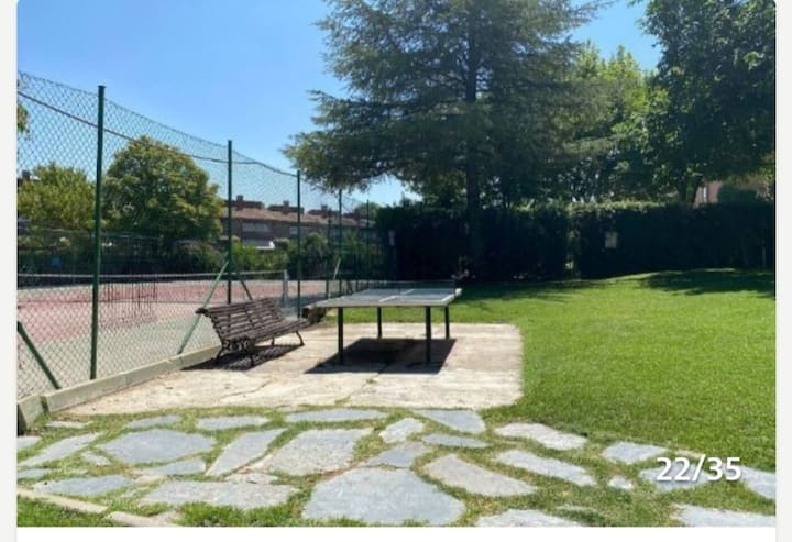 Jardín común con césped, columpio y pista deportiva al fondo: zonas comunes para disfrutar en familia.