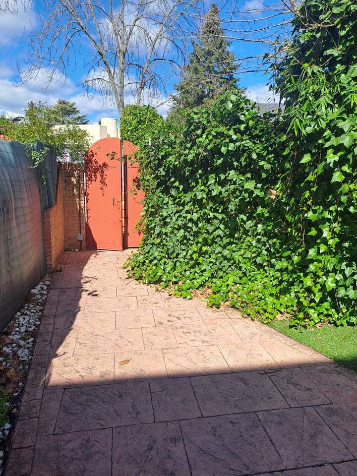 Acceso exterior con puerta roja y vegetación: entrada independiente y muy cuidada.
