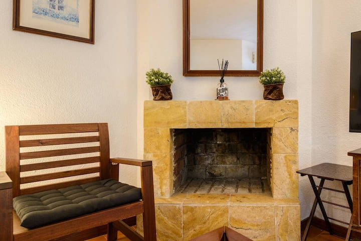 Detalle de la chimenea de piedra con sillón de madera: el rincón favorito de la casa.