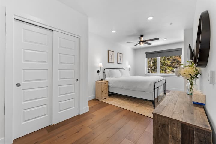 Primary bedroom with king sized bed, mounted smart TV, en suite bathroom and sitting area. 