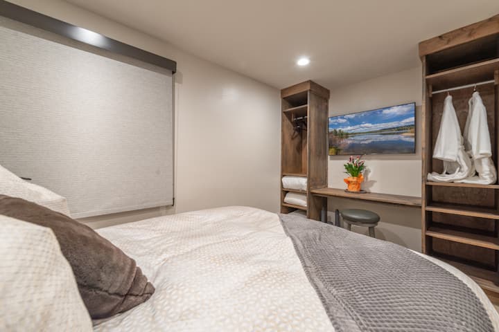 Lit king size confortable avec literie Ralph Lauren, télévision connectée et coin bureau dans la chambre principale.