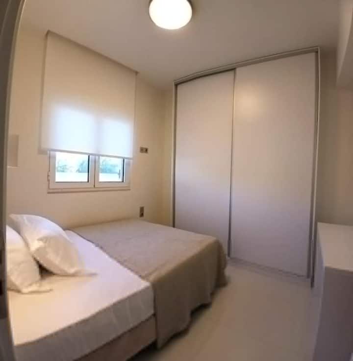 Pokojná spálňa Retreat. Pokojná a útulná spálňa s teplými neutrálnymi tónmi, mäkkou posteľnou bielizňou a dostatočným úložným priestorom. Veľká vstavaná skriňa a prirodzené svetlo vytvárajú pohodlnú atmosféru, ktorá zaisťuje pokojné noci a osviežujúci začiatok každého dňa.