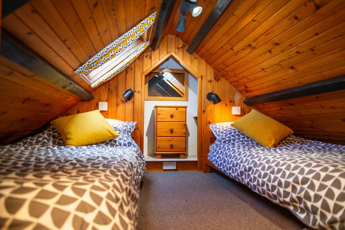 Спалня на горния етаж с наклонен таван и две единични легла