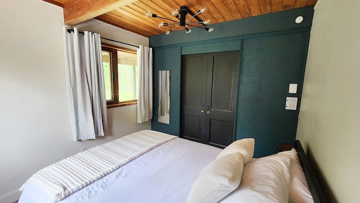 The Spa View Bedroom on the first floor features a comfy queen bed and a wide doorway for easy accessibility, offering a cozy and convenient retreat with serene views at The Hideaway.