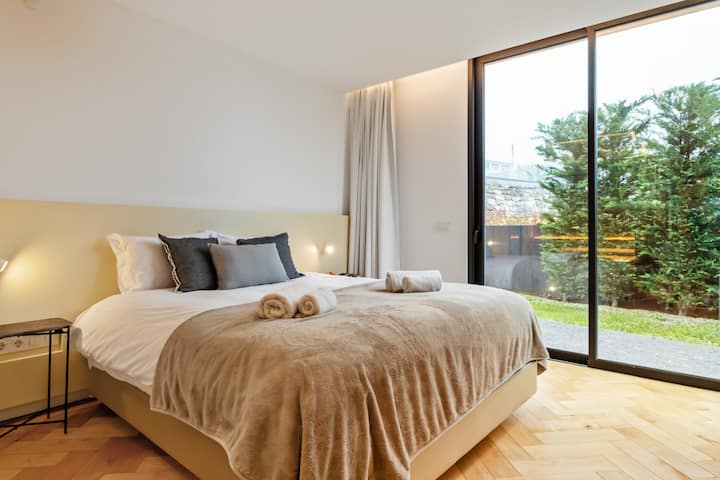 Relájate en un tranquilo dormitorio de Madeira donde los tonos suaves, las texturas cálidas y las vistas al jardín crean una sensación de confort.