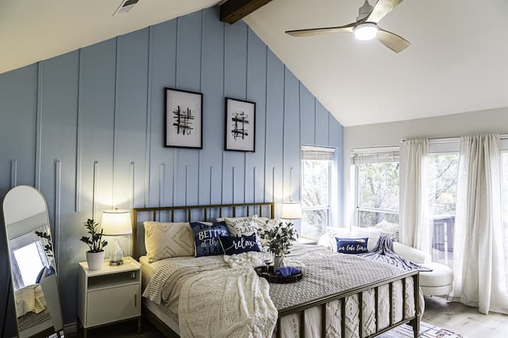 In this beautiful master bedroom with its chaise lounge, lake view, and luxurious master bath, every element is carefully curated to create a serene and inviting retreat where you can escape the world and indulge in the ultimate comfort and relaxatio