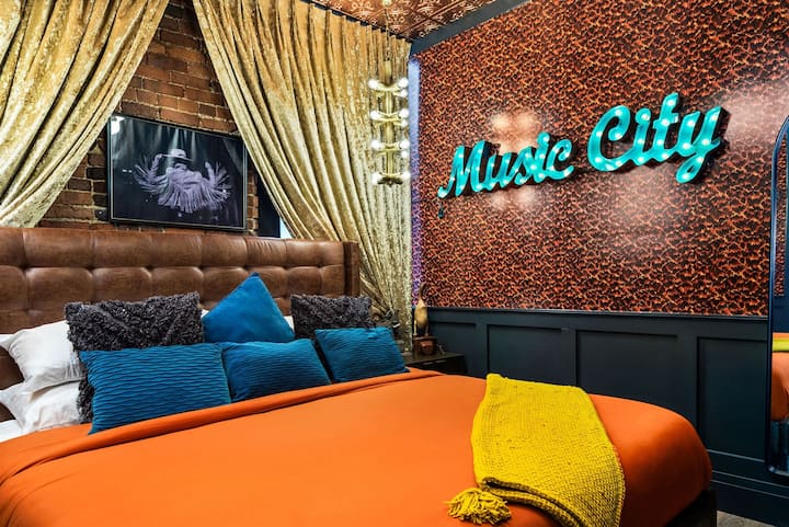 - Alama ya neon ya Music City inang'aa juu ya kuta zenye muundo wa ujasiri na mikwaruzo tajiri - Matandiko ya kitani na mapazia ya dhahabu huinua muundo wa chumba cha kulala - Nafasi bora yenye mada na kina cha rangi na lafudhi maridadi