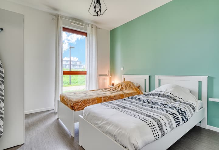 Chambre avec deux lits simples, dressing et table à repasser