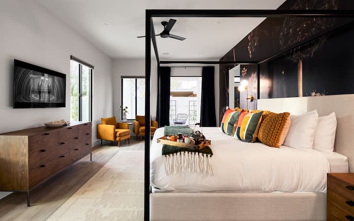 (1er piso) Dormitorio principal con cama tamaño king, TV inteligente, espacio de descanso, decoración de diseño, acceso al patio y baño privado.