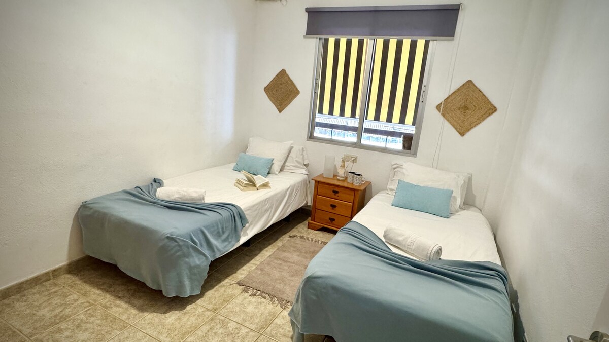 ห้องนอนพร้อมเตียงเดี่ยวสองเตียงและตู้เสื้อผ้า หน้าต่างหันหน้าไปทางระเบียงของที่พัก