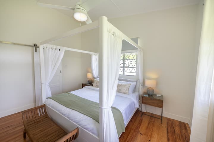 تحتوي غرفة النوم الهادئة على سرير أوروبي بأربعة أعمدة بحجم سوبر كينج مع ستائر جيدة التهوية.