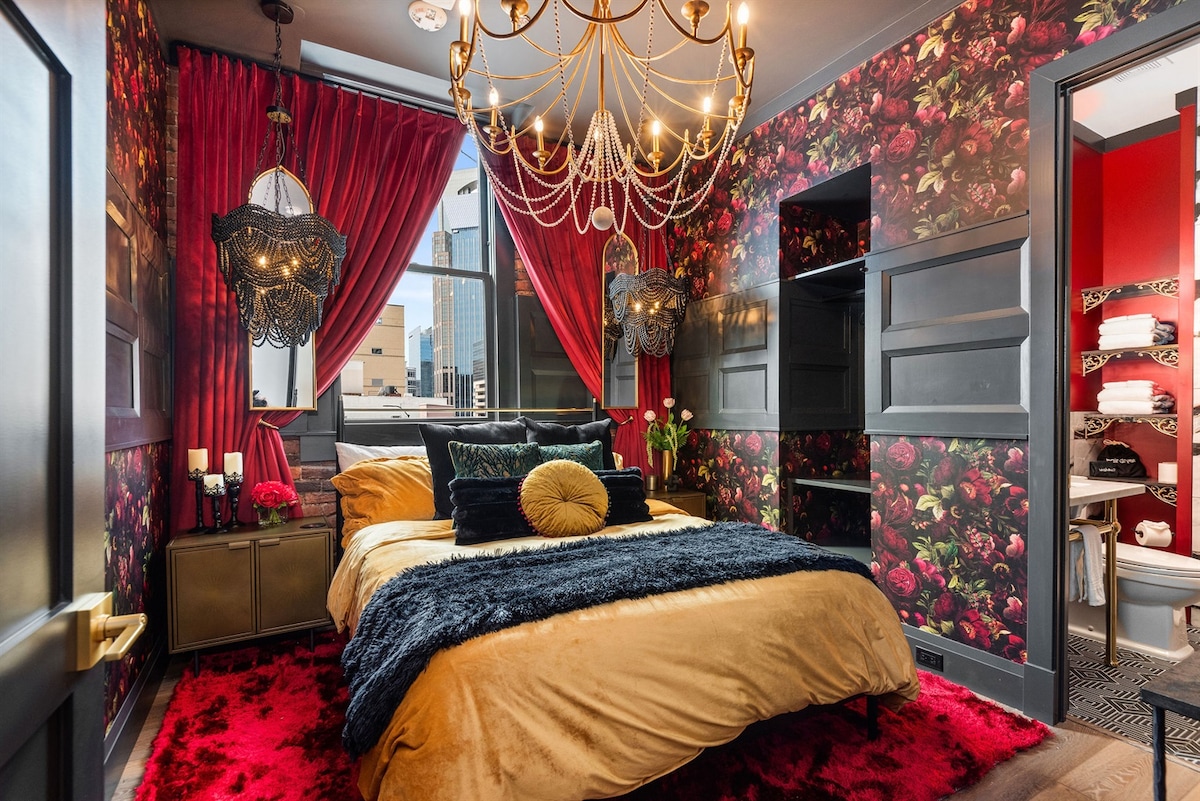 - Dramatic bedroom with rich florals and velvet red drapes   - Warm lighting, plush bedding and bold décor create a retreat   - Cozy space offering style, comfort and unforgettable charm