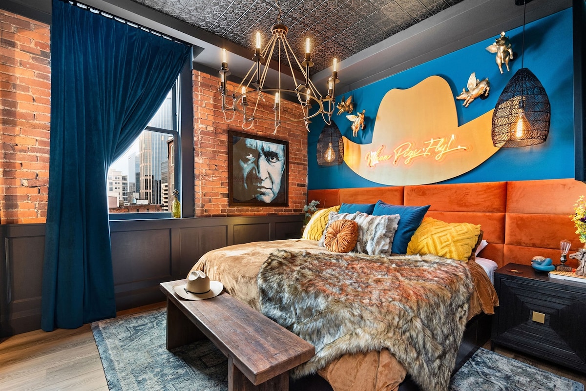 - Stylish bedroom with brick walls and vibrant art décor   - Plush bedding, neon sign and warm textures for a cozy stay   - Trendy retreat with striking colors and inviting charm