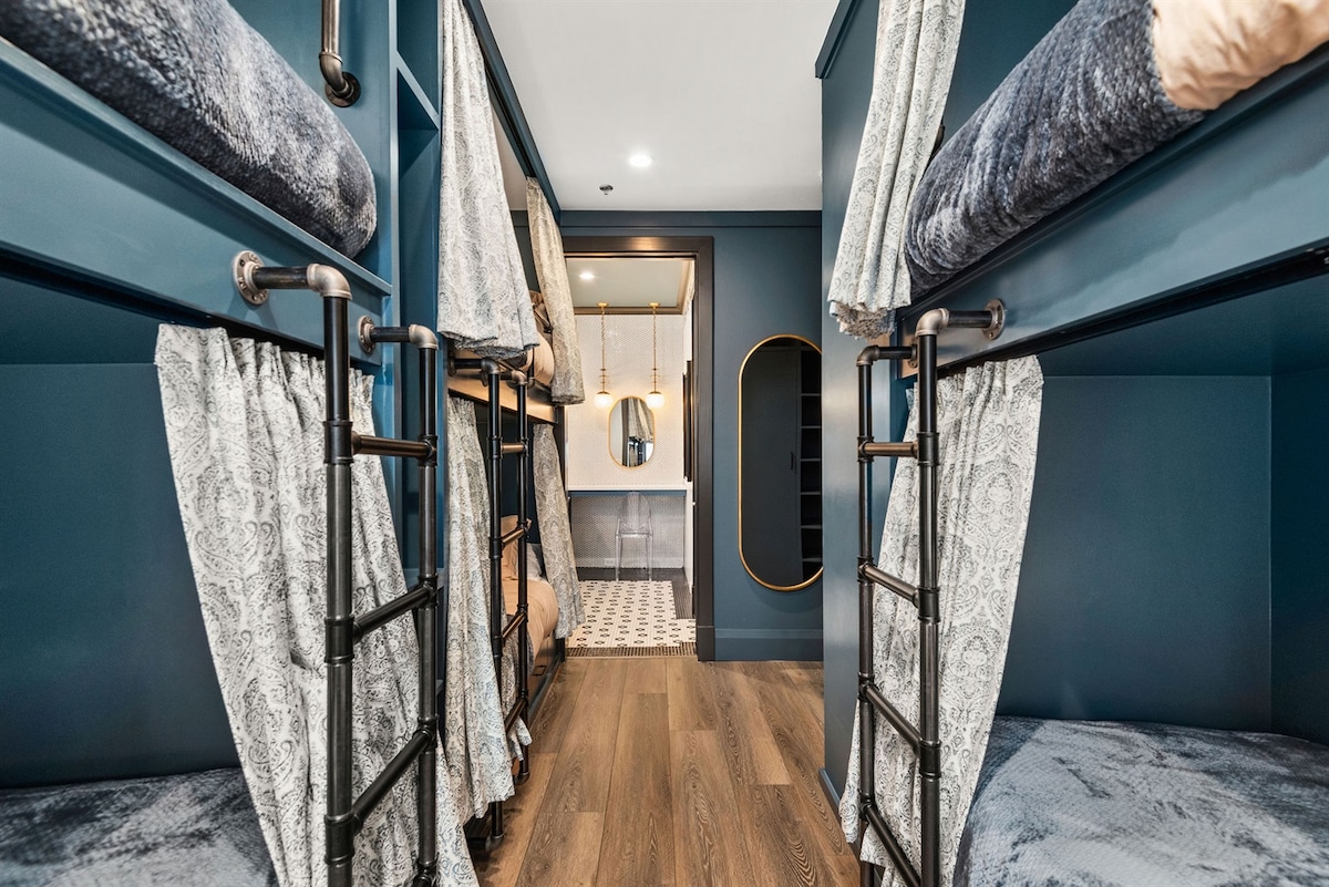 - Bunk room with cozy beds and deep blue built-ins   - Soft lighting and private curtains create a relaxing setup   - Perfect space for groups needing comfort and stylish rest