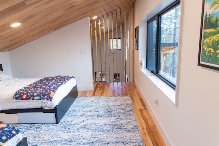 Loft space is open to the living room below through the wood slats.