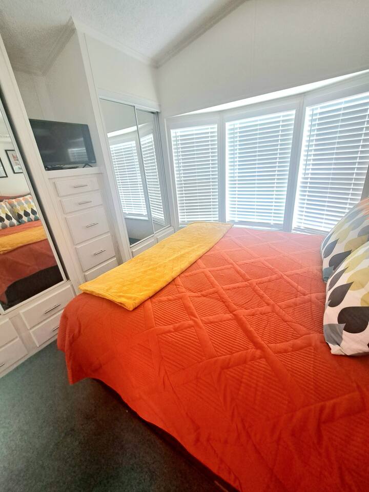 Chambre principale avec lit Queen Size, surmatelas de six pouces et télévision.