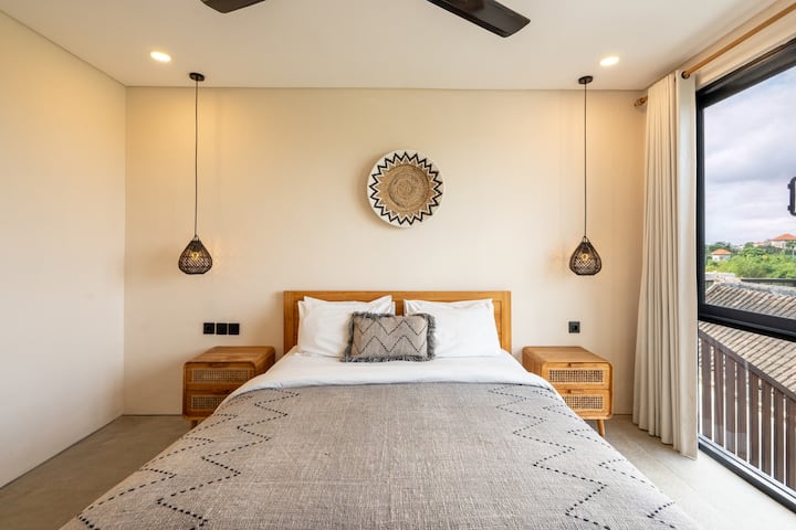 Uitnodigende slaapkamer omlijst door warme tinten en rotan details.