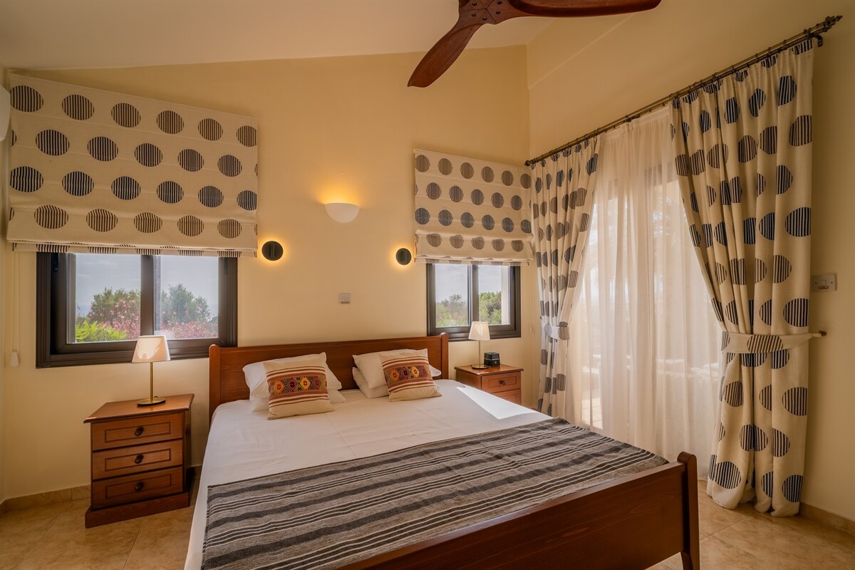 غرفة نوم رئيسية بحمام داخلي مع إطلالات على البحر وإمكانية الوصول إلى التراس. سرير بحجم كينج، ومروحة سقف، ووحدة تكييف/تدفئة مخصصة، ومنضدة، وخزائن ملابس كبيرة مدمجة، ومكبر صوت بلوتوث/منبه.