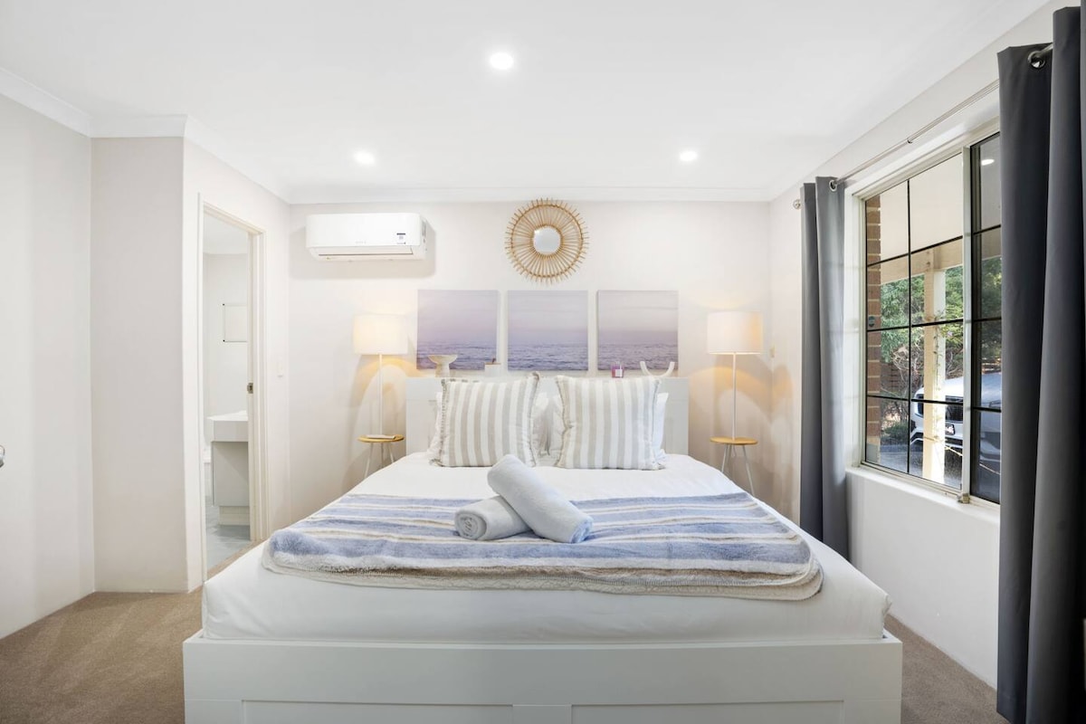 Acogedora habitación tamaño queen con ropa de cama suave e iluminación cálida.