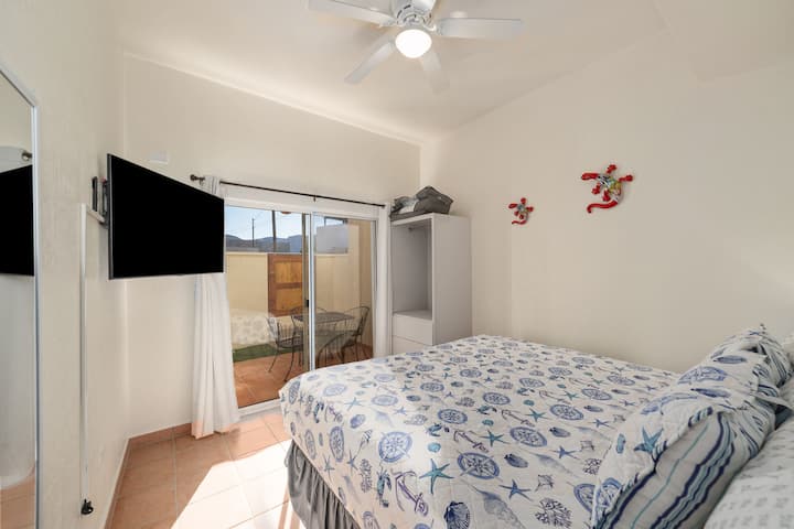 Dormitorio dos de la planta baja: cuenta con una acogedora cama tamaño king, ventilador de techo y un armario abierto sencillo con cortinas.