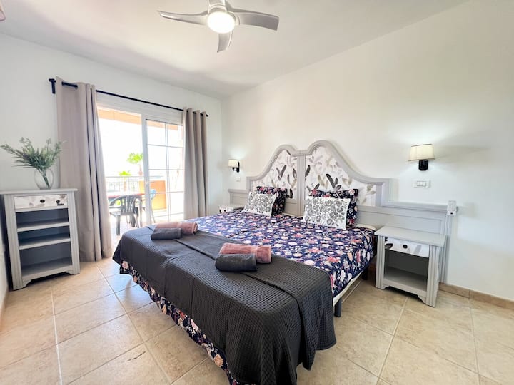 ห้องนอนพร้อมเตียงควีนไซส์พัดลมเพดานและตู้เสื้อผ้า