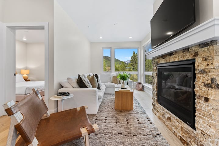 Sala de estar que ofrece muebles acogedores, chimenea de gas, TV de pantalla plana montado y grandes ventanales con vistas increíbles. 