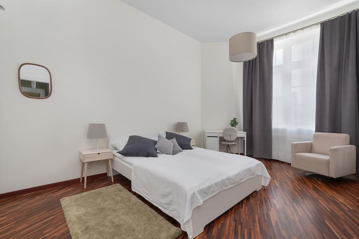  Pohodlná posteľ v spálni s elegantnou posteľnou bielizňou a štýlovým osvetlením, ktoré zabezpečujú pokojný spánok.