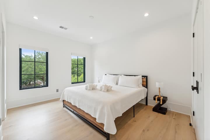 Svetlá moderná spálňa v pobrežnom štýle s manželskou posteľou king, sprchovacím kútom so sklenenými stenami a vlastnou kúpeľňou v pokojnom prostredí