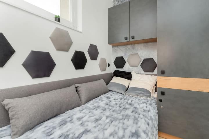 卧室内有一张单人床，床头板采用黑白六边形设计。 布局呈现出对称的几何图案，非常有趣。