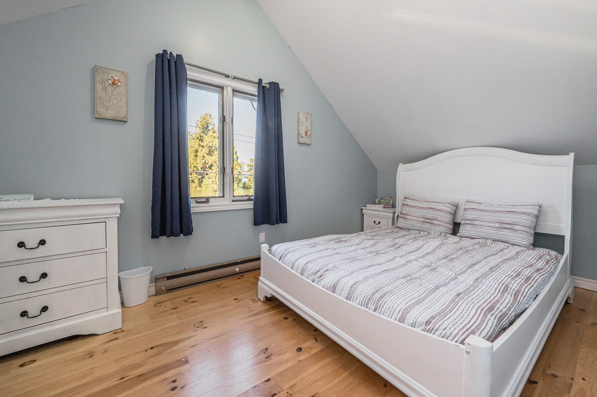 Ontspan in de hoofdslaapkamer met een comfortabel wit bedframe, bijpassend dressoir en marineblauwe gordijnen – het creëren van een gezellig en rustig toevluchtsoord na een dag verkennen.