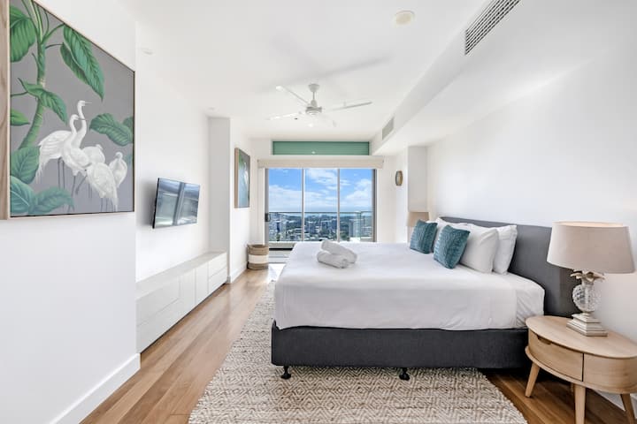 Hlavná spálňa s luxusnou manželskou posteľou, posuvnými dverami na balkón a televízorom.