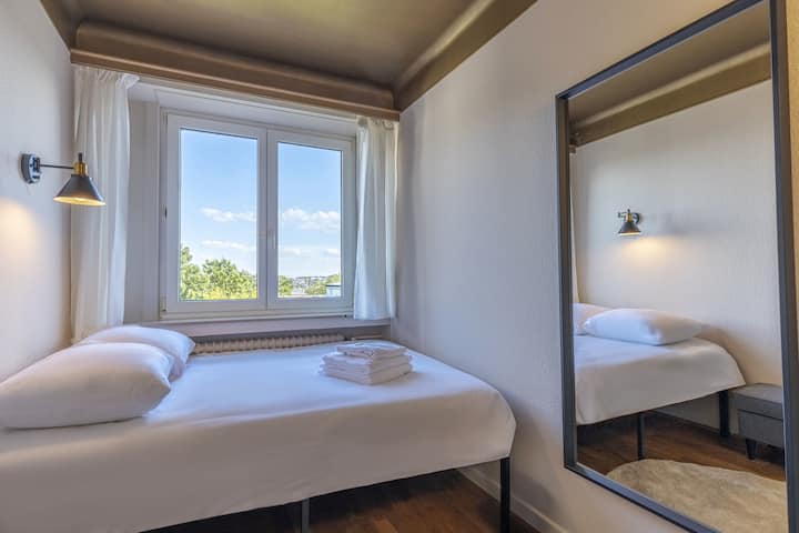 Acogedor dormitorio individual con amplia luz natural, con una cama cómoda y un gran espejo para un espacio acogedor y funcional.