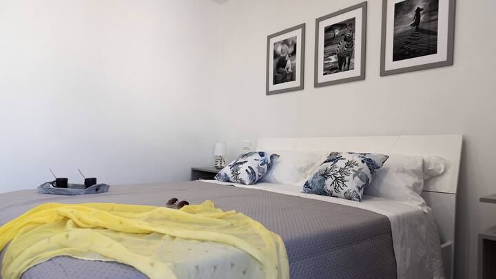 Საძინებელი, რომელიც აივანს გადაჰყურებს მცირე სამუშაო სივრცით