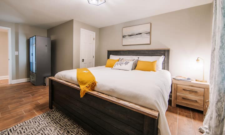 ห้องนอนชั้นล่างมีเตียงขนาดคิงไซส์หรูหรา เตียงเด็กแพ็คแอนด์เพลย์ ตู้เสื้อผ้าสไตล์โมเดิร์นที่มีไฟส่องหลัง และเครื่องปรับอากาศและเครื่องทำความร้อนแบบติดผนังแยกต่างหาก 