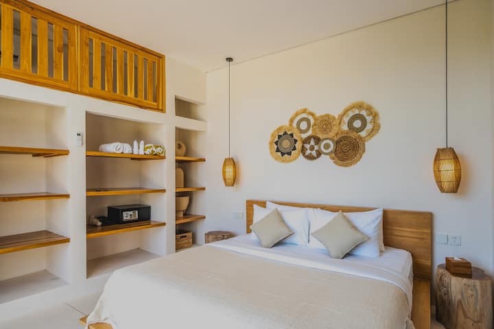 Тази спокойна спалня съчетава комфорт и стил, с дървена стена за естествено докосване и рафтове за лични акценти