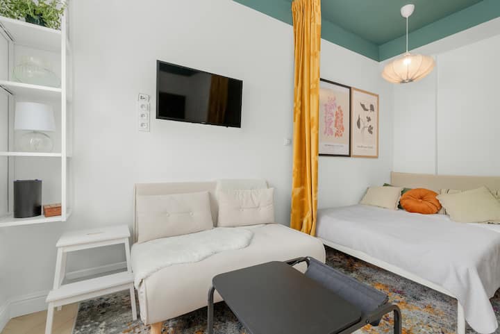 พื้นที่นั่งเล่นและนอนรวมกัน มีเตียง โซฟา และทีวีติดผนัง

