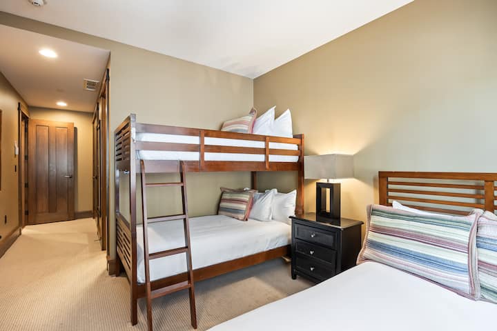 - Perfecto para niños o grupos, este dormitorio cuenta con una litera doble sobre una completa más una cama adicional.
- La iluminación suave y los cojines a rayas agregan un carácter alegre a este cómodo espacio
- El acceso al pasillo y el espacio en el armario mantienen la habitación práctica y privada.