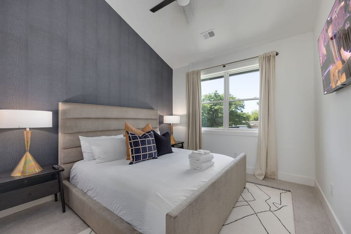 יחידה עליונה - קומה 2: חדר שינה שני עם מיטת קינג-סייז, מרחב ארון, טלוויזיה חכמה ותקרה קמורה גבוהה.