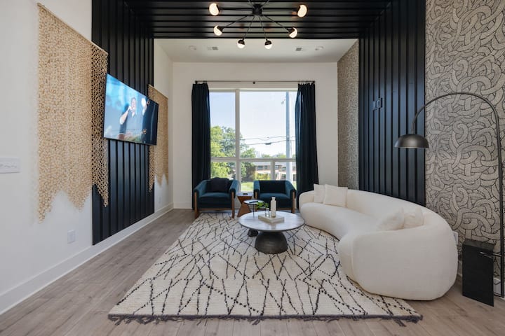 היחידה העליונה - קומה 1: סלון מודרני וטרנדי המעוטר בריהוט ועיצוב מעוצבים עם תקרה גבוהה, חלונות גדולים וטלוויזיה חכמה לבידור.