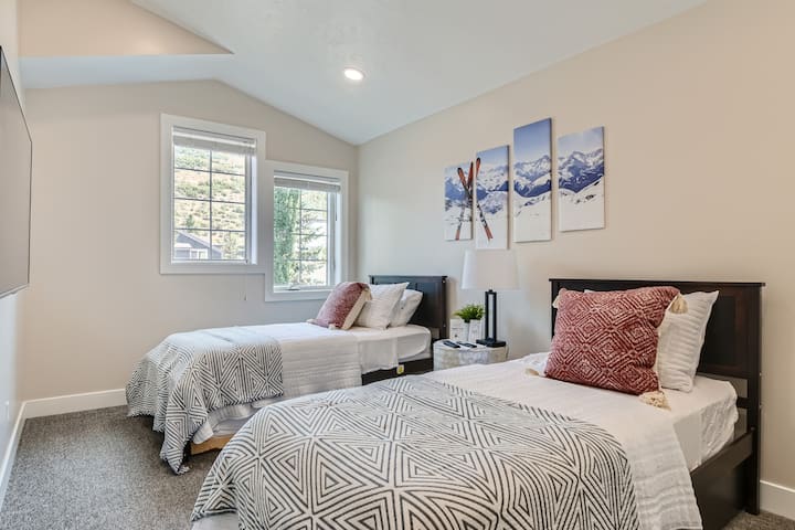 Dormez profondément dans cette chambre lumineuse avec deux lits jumeaux confortables et deux lits gigognes, un plafond voûté et des œuvres d'art de ski amusantes.
