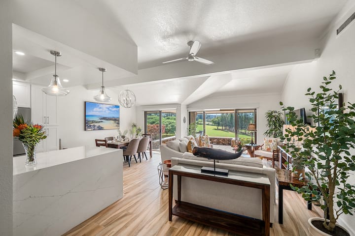 Esta sala de estar de concepto abierto ofrece un diseño moderno, abundante luz natural e impresionantes vistas de una exuberante vegetación y campos de golf.