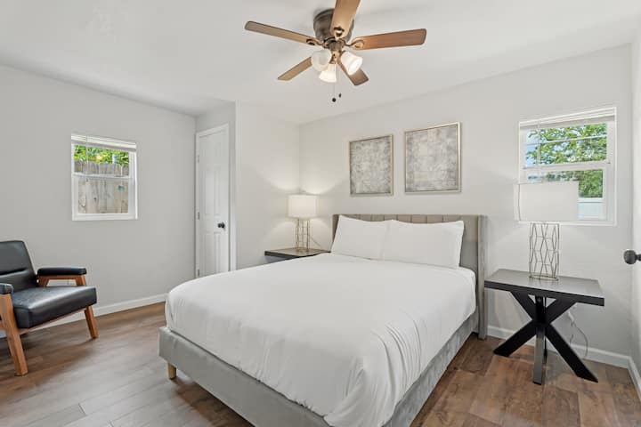 חדר שינה מודרני עם מיטת קווין סייז, תאורה מעוצבת וחלונות כפולים לשהייה מוארת ומאווררת.