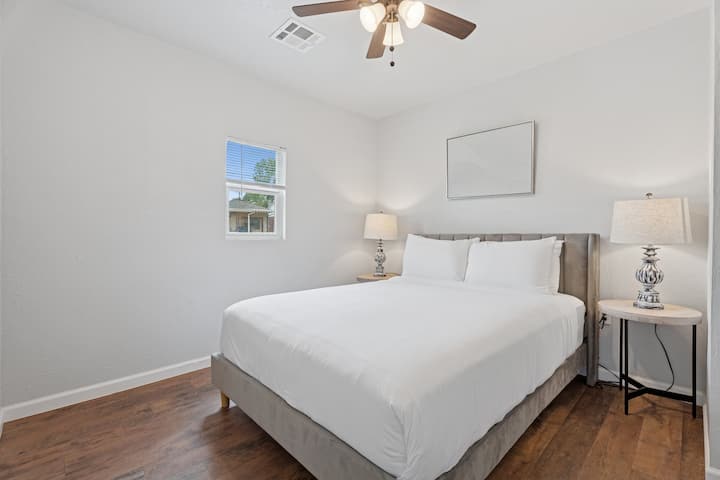 חדר קווין-סייז מואר ונוח עם עיצוב ניטרלי ונופים של שכונה שלווה.